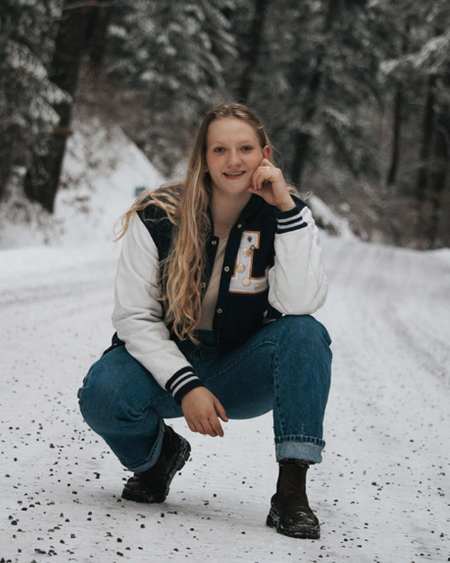 Lily poses in the snowy outdoors in her letter jacket